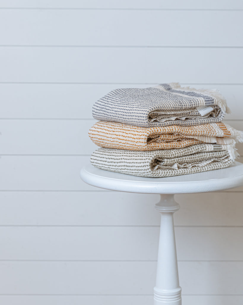Stack of Turkish waffle bath towels in beige color variations, folded on a stool