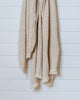 Sand-colored linen and Turkish cotton throw with textured weave hanging on white wall