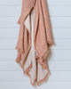 Terracotta and ecru muslin cotton throw with naturally crinkled texture and delicate fringes, hanging on white wall