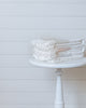 Stack of ivory Turkish cotton waffle bath towels with soft stripes on white stool