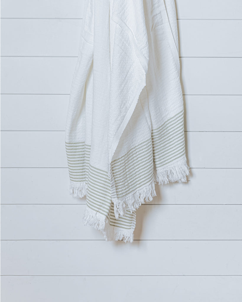 Ivory Turkish cotton waffle towel with sauge stripe displayed hanging on white wall