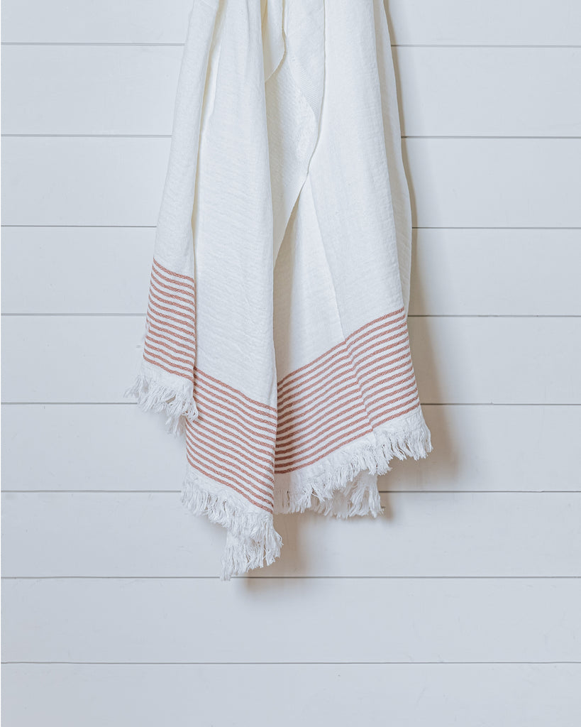 Ivory Turkish cotton waffle towel with terracotta stripe displayed hanging on white wall