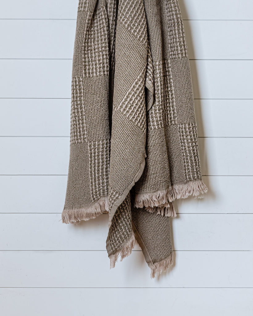 Soft khaki and beige cotton throw blanket with waffle texture and fringes