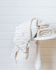 Ivory bamboo and cotton throw blanket folded on white wooden stool