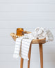 Off-white bamboo and cotton hand towels with subtle stripes folded on wooden stool