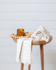 Off-white striped bamboo hand towel draped over bathroom sink with wooden cabinet and décor