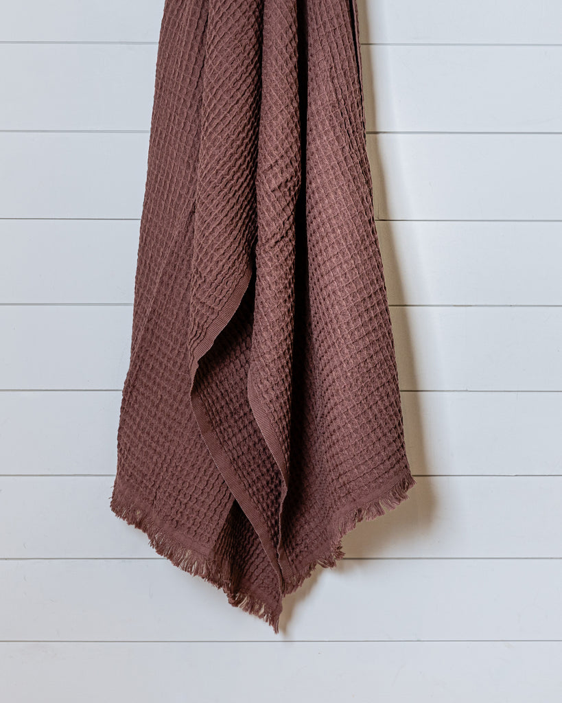 Bordeaux red Turkish waffle bath towel displayed hanging against white wall
