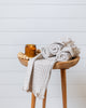 Light pearl grey waffle cotton hand towel rolled on wooden stool