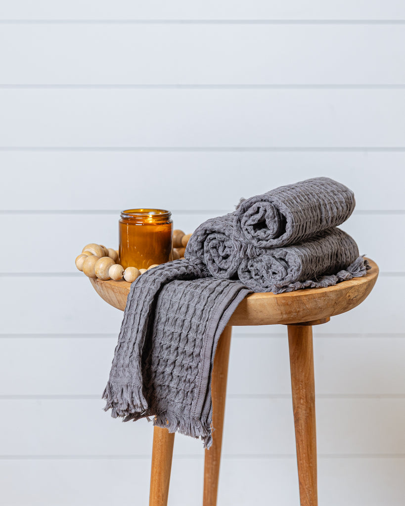 Warm taupe waffle-textured cotton hand towel displayed on wooden stool
