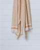 Beige and mustard yellow Turkish waffle bath towel displayed hanging against white wall