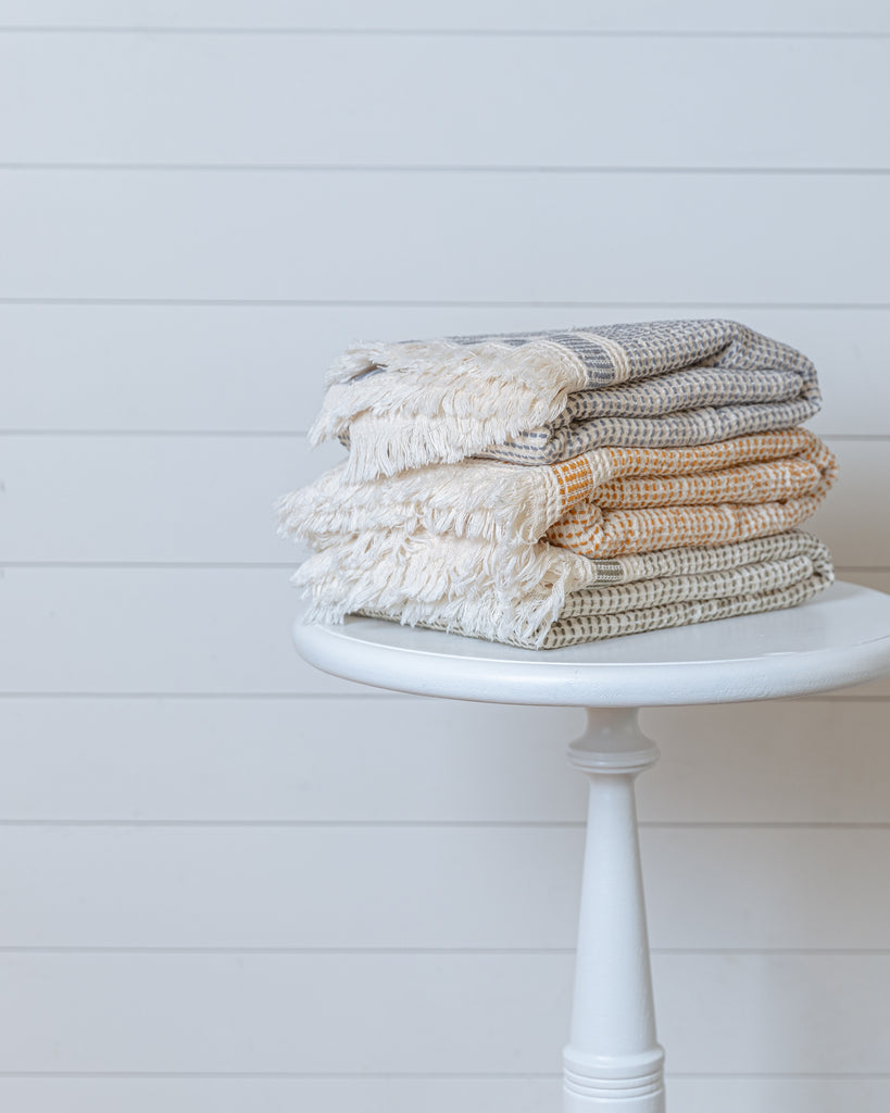 Stack of Turkish waffle bath towels in beige color variations, folded on a stool