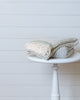 Ivory Turkish cotton bath towel with stripes folded on white stool