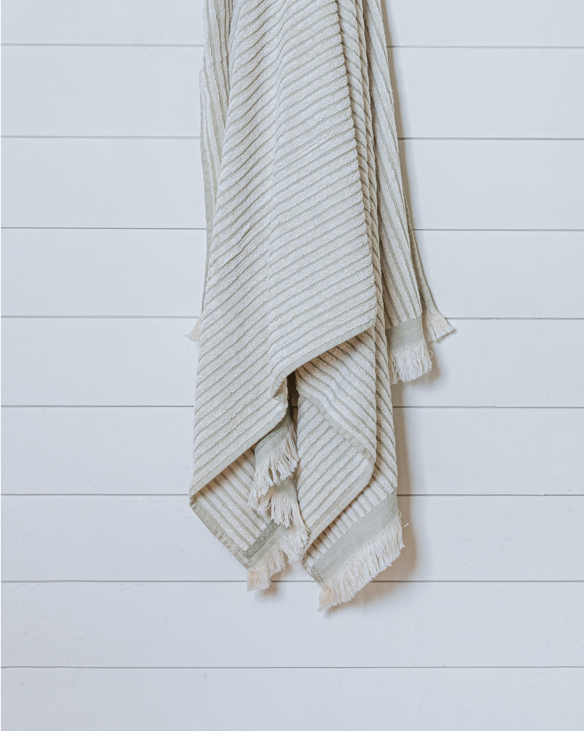 Textured ivory Turkish cotton bath towel with sauge border hanging neatly